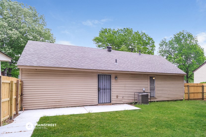 the front of a brown garage with a yard and a wooden fence