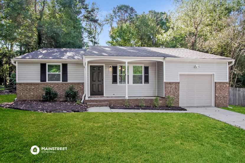 a small white house with a lawn and a driveway