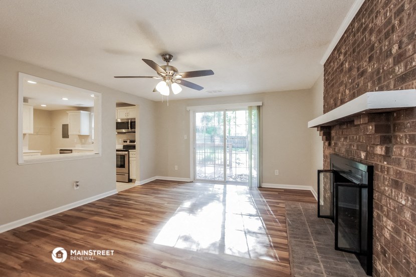 an empty living room with a fireplace and a ceiling fan