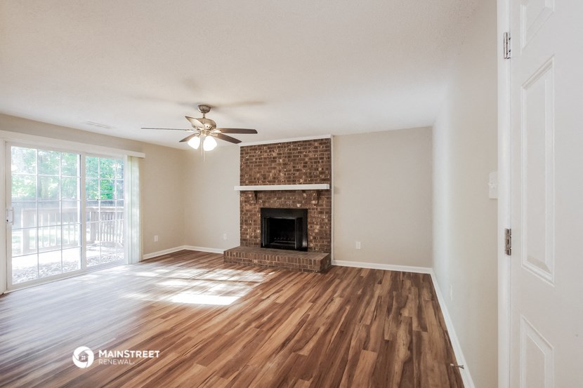 an empty living room with a fireplace and a ceiling fan