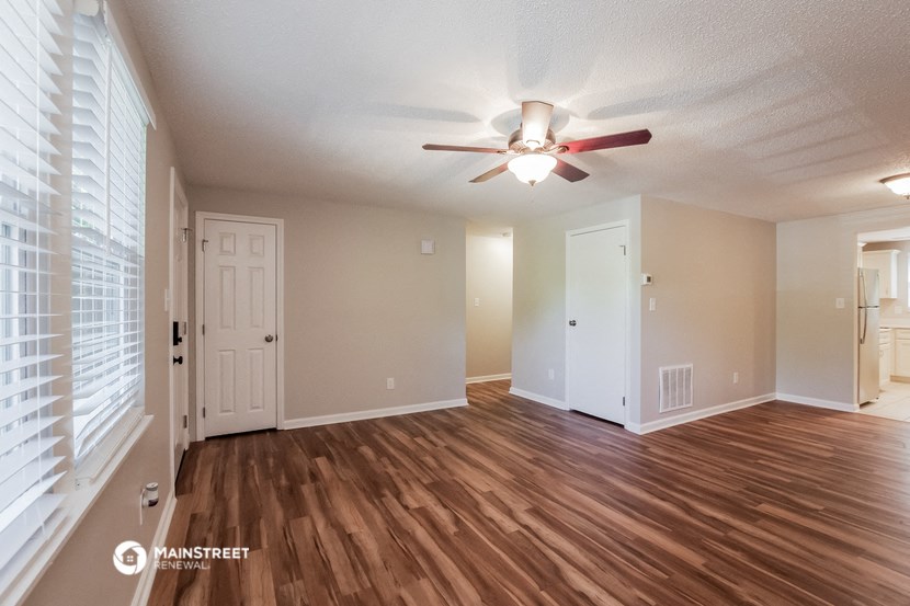 an empty living room with a ceiling fan and wood flooring