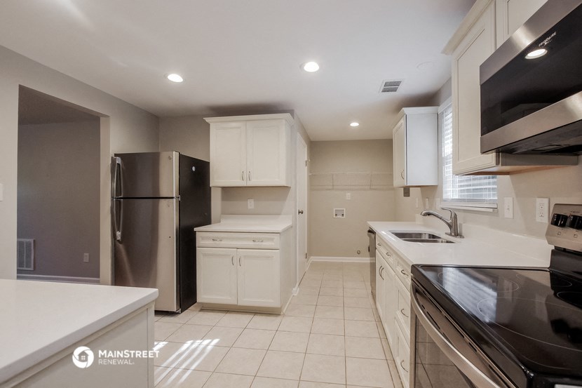 a white kitchen with stainless steel appliances and white counter tops