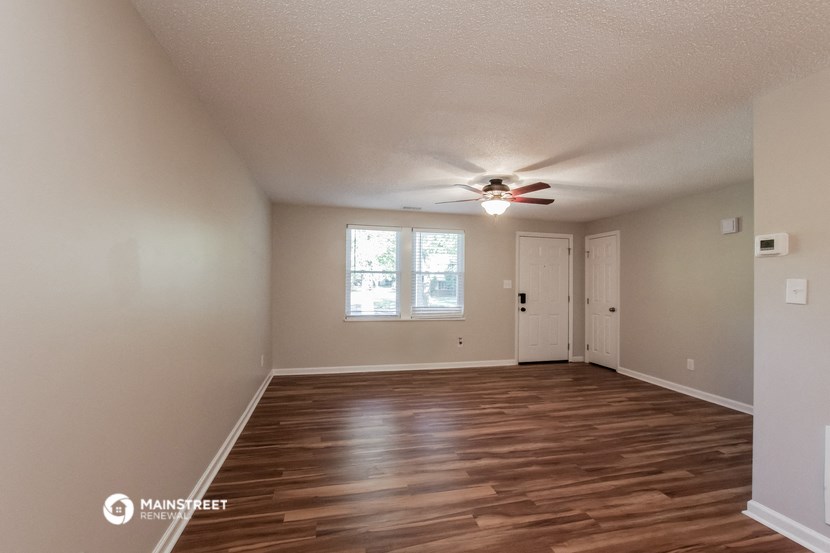 the spacious living room with wood flooring and a ceiling fan
