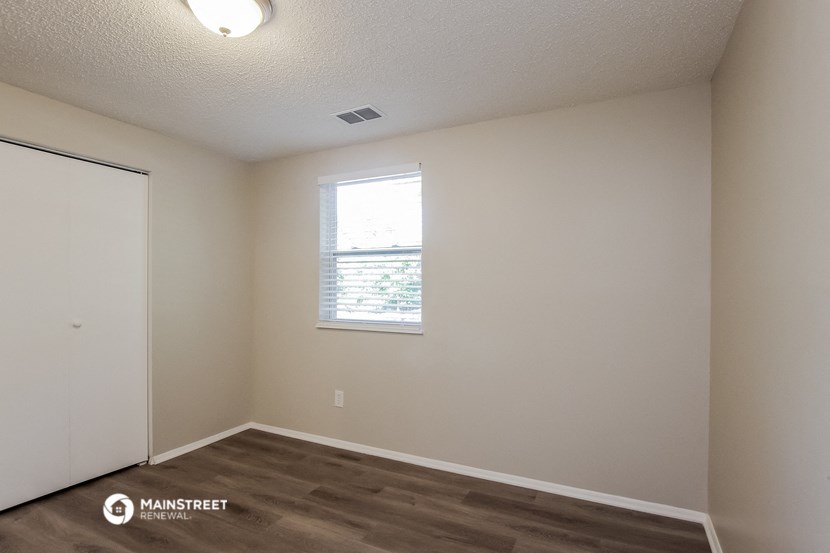 the upstairs bedroom of an apartment with a window and wood flooring