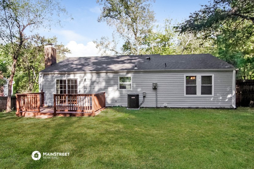 a backyard with a white house and a deck
