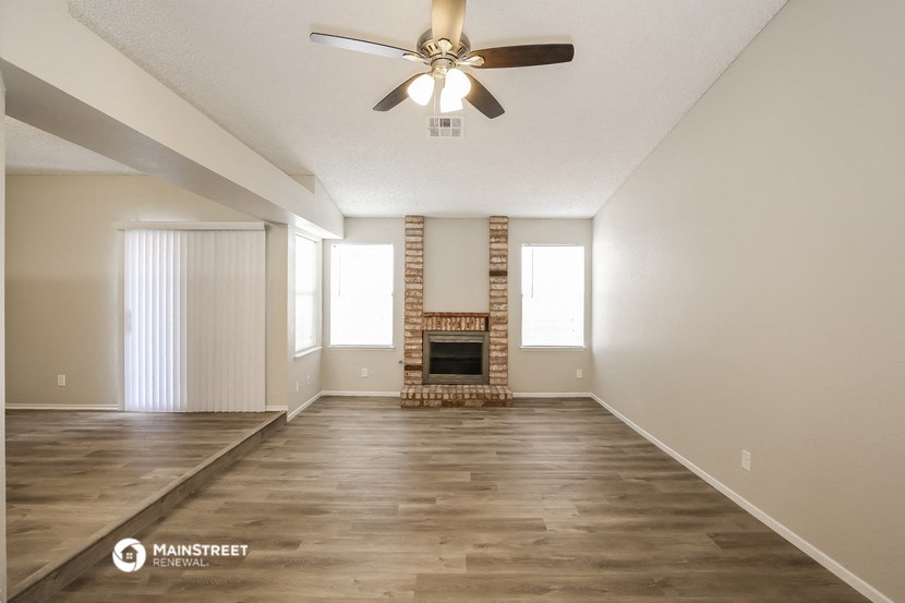 an empty living room with a ceiling fan and a fireplace