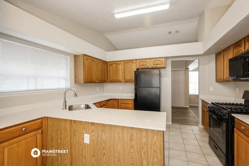 a kitchen with a white counter top and a black refrigerator