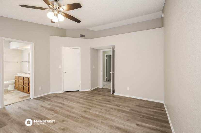 a spacious living room with a ceiling fan and a bathroom