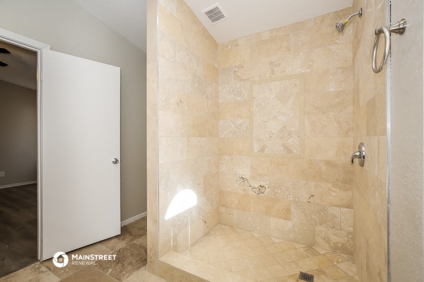 a walk in shower in a bathroom with tiled floors and a shower stall with