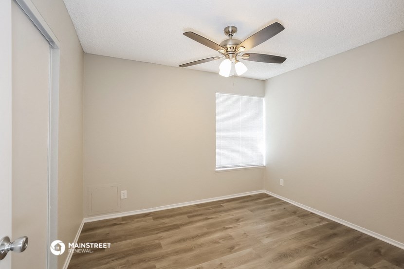 an empty room with a ceiling fan and a window