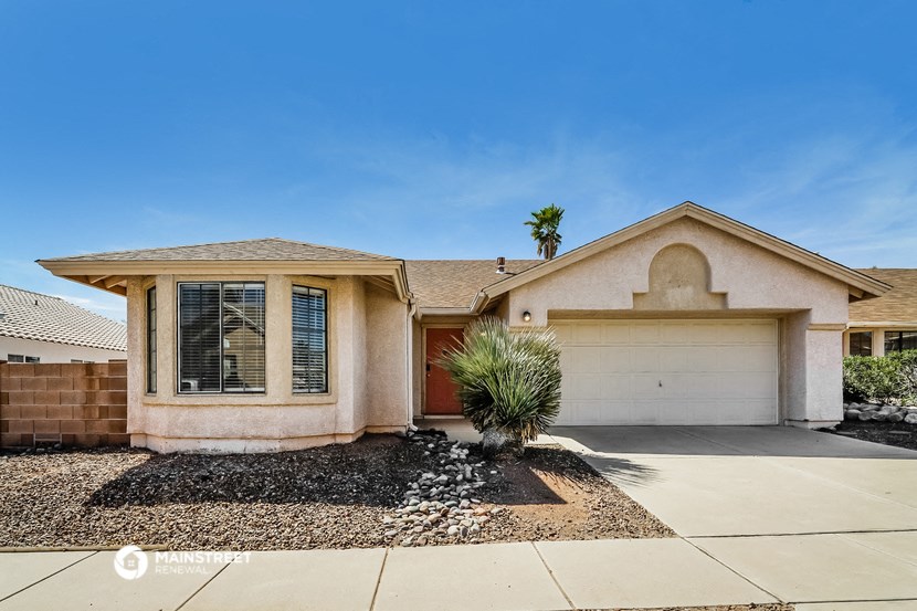 a beige house with a garage and a palm tree