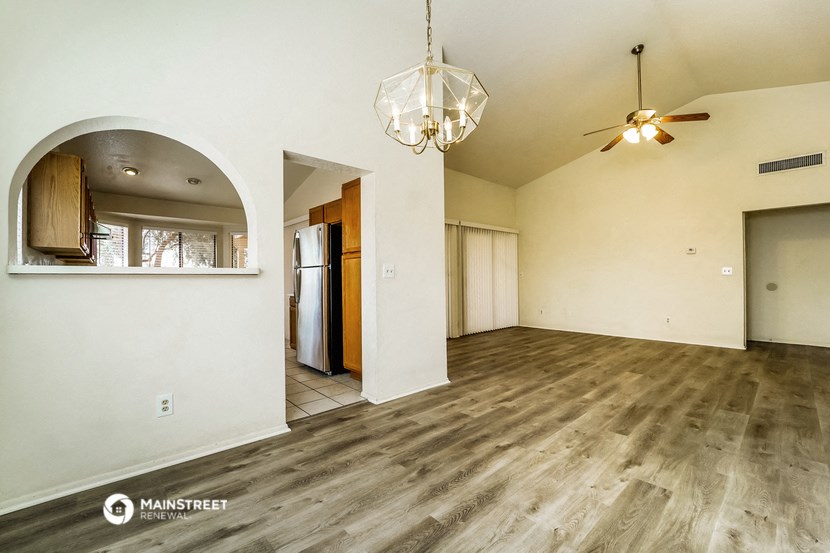 the living room and dining room of a house with white walls and wood floors