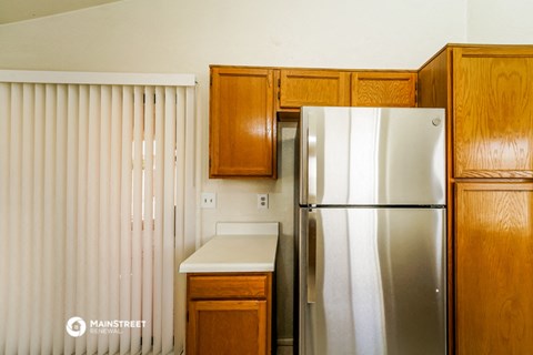 a kitchen with a refrigerator and wooden cabinets
