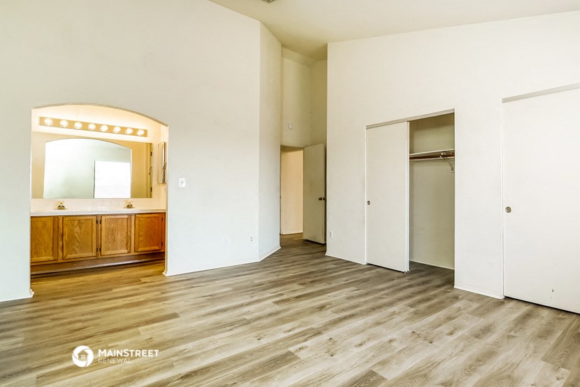 an empty living room with white walls and wooden floors and a bathroom