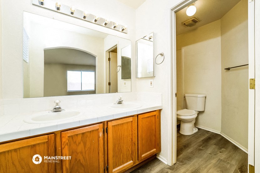 a bathroom with two sinks and a toilet and a large mirror