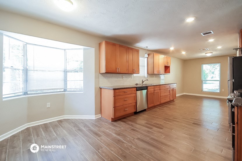an empty kitchen with wood floors and wooden cabinets