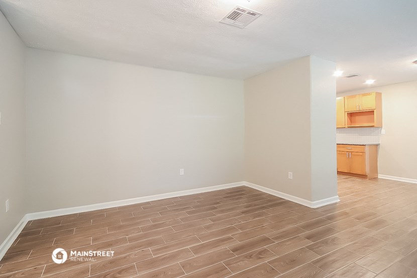 the spacious living room with wood flooring and a kitchen
