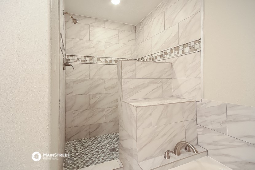 a walk in shower in a white tiled bathroom