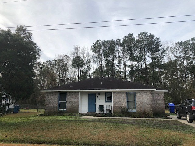 A small house with a white door and a blue door is surrounded by trees.
