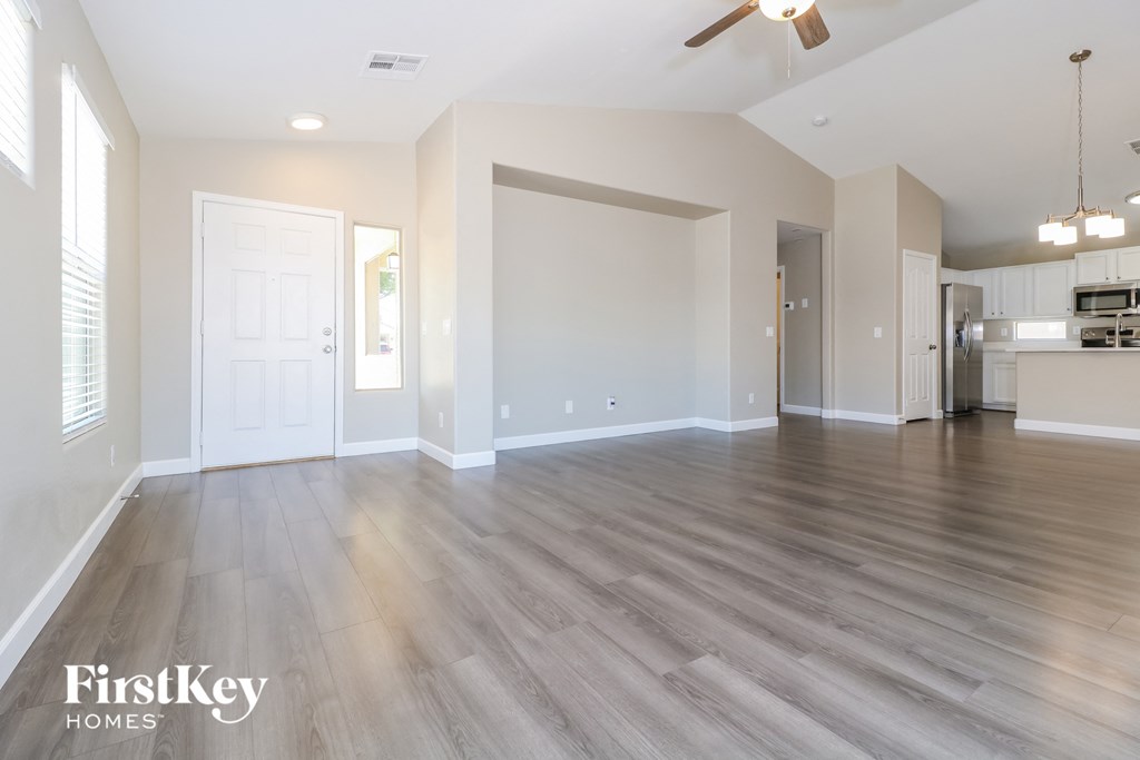 A spacious room with wooden flooring and a ceiling fan.