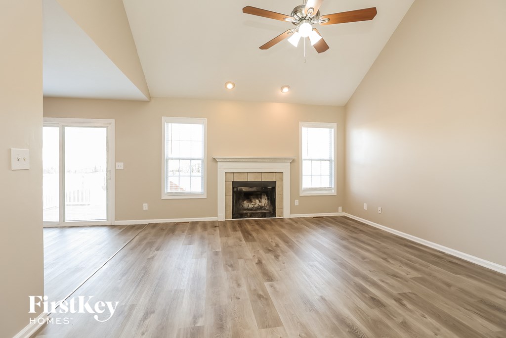 an empty living room with a fireplace and a ceiling fan