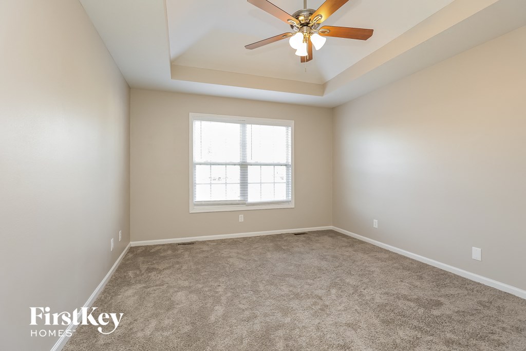 an empty room with a ceiling fan and a window
