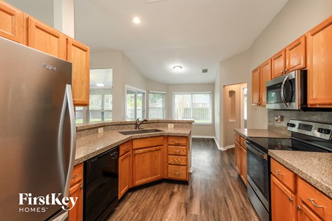 full kitchen with granite counter tops and stainless steel appliances and wood flooring