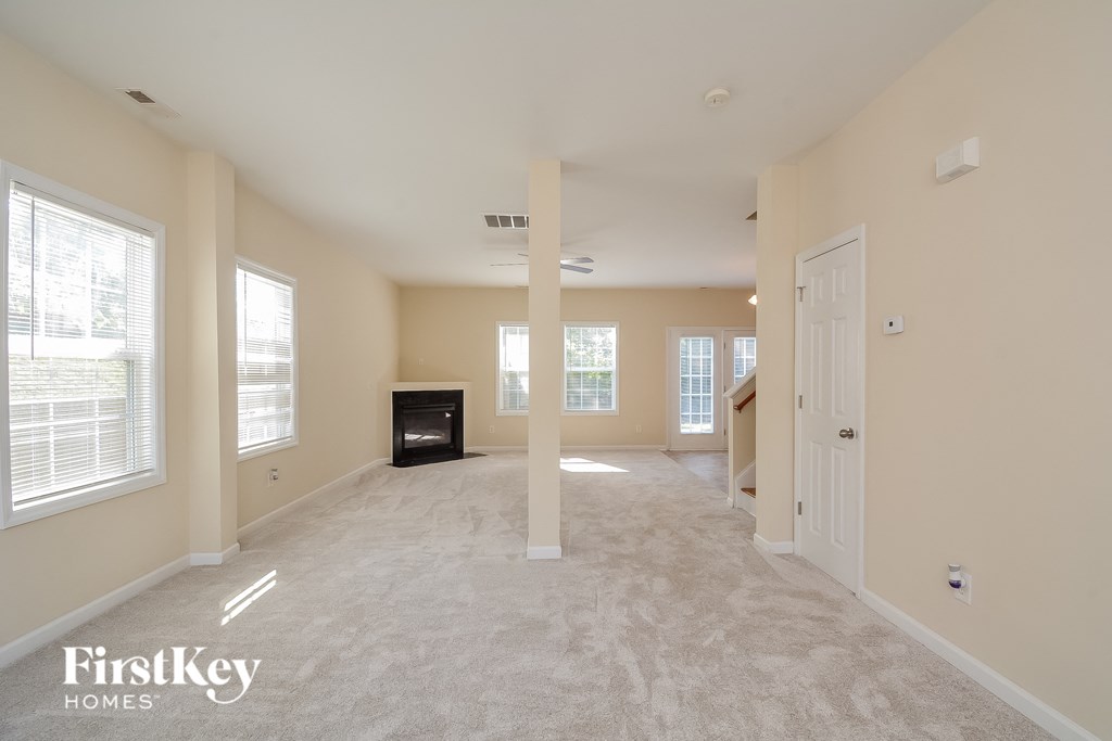 an empty living room with a fireplace and windows