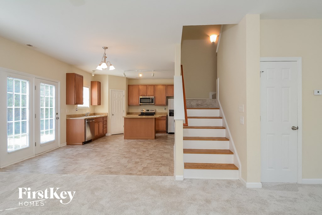 an open kitchen and living room with stairs leading to a