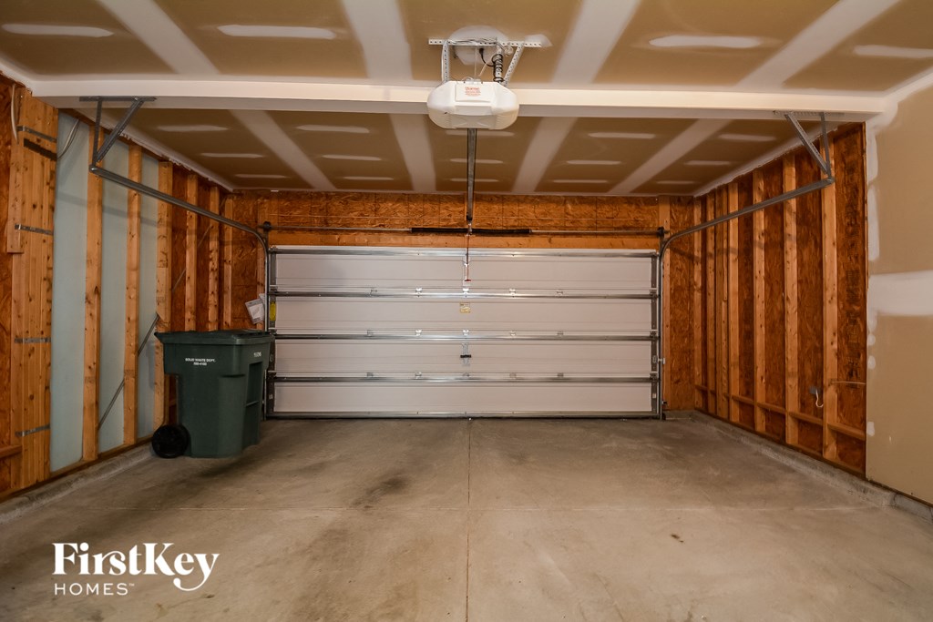 a garage with a gray garage door and a green trash can