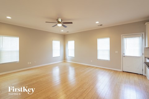 A spacious room with wooden floors and a ceiling fan.