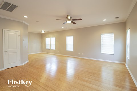 A spacious room with wooden floors and a ceiling fan.