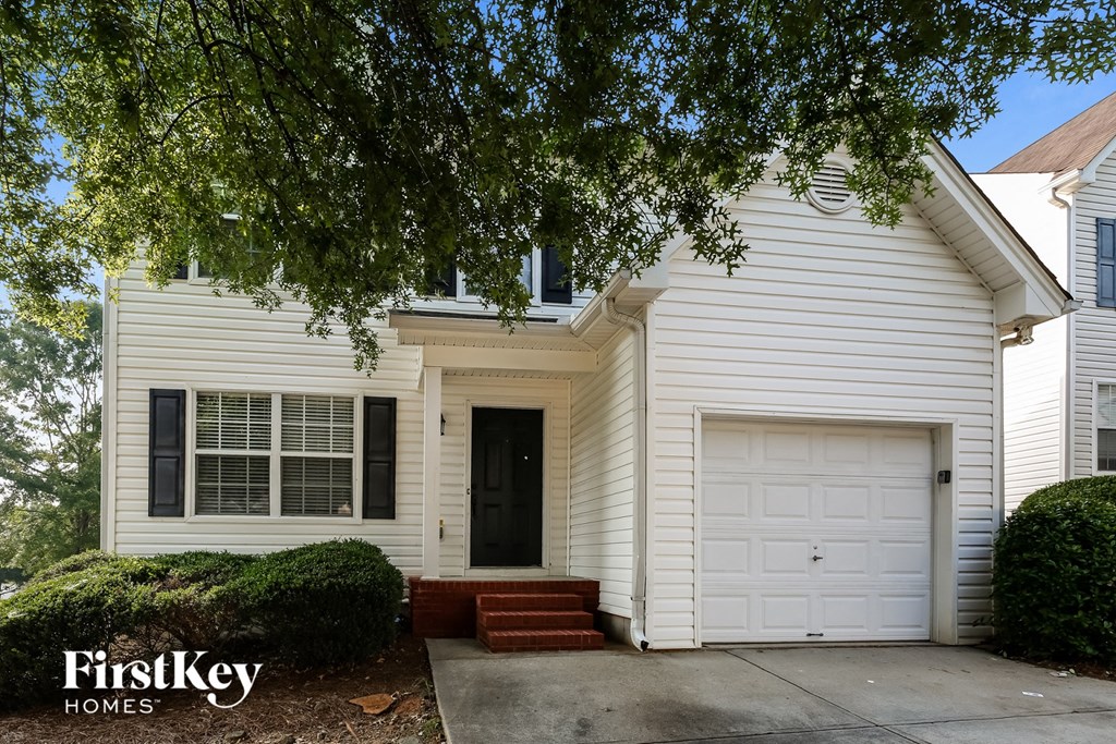 A white house with a black door and a garage door.