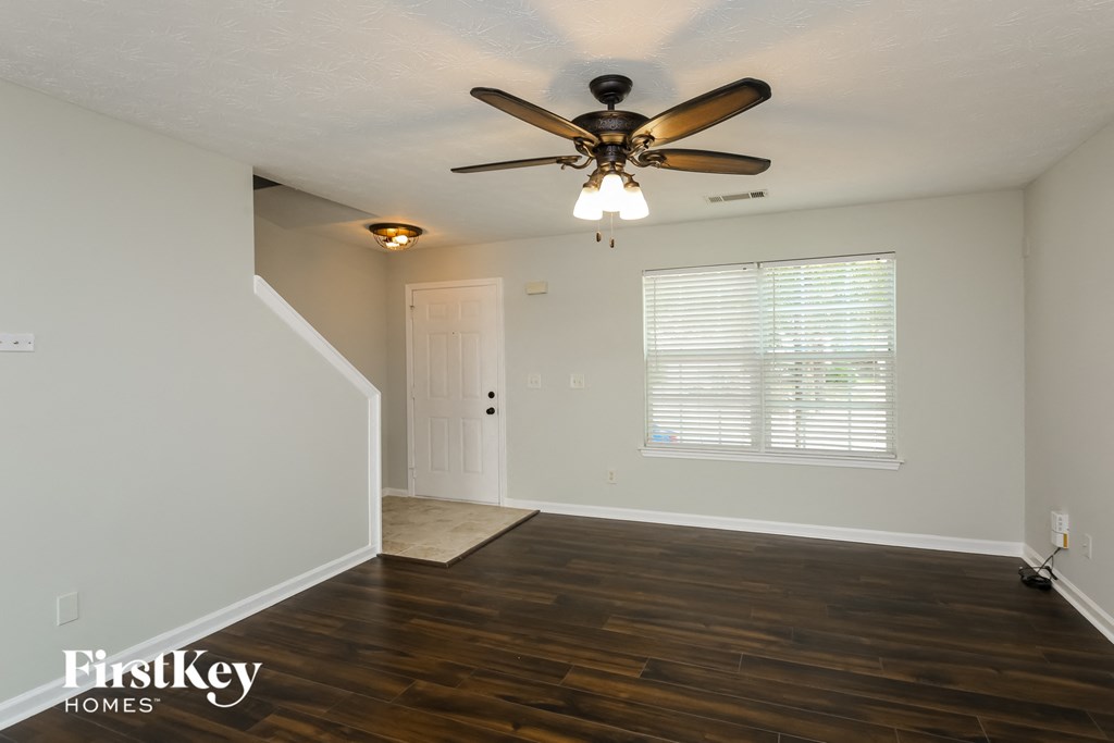 A room with a ceiling fan and wooden floors.