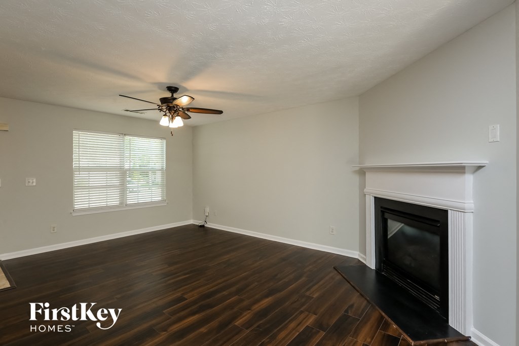 A living room with a fireplace and a ceiling fan.
