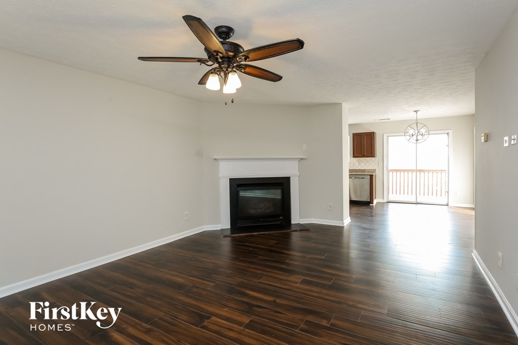 A spacious living room with a fireplace and a ceiling fan.
