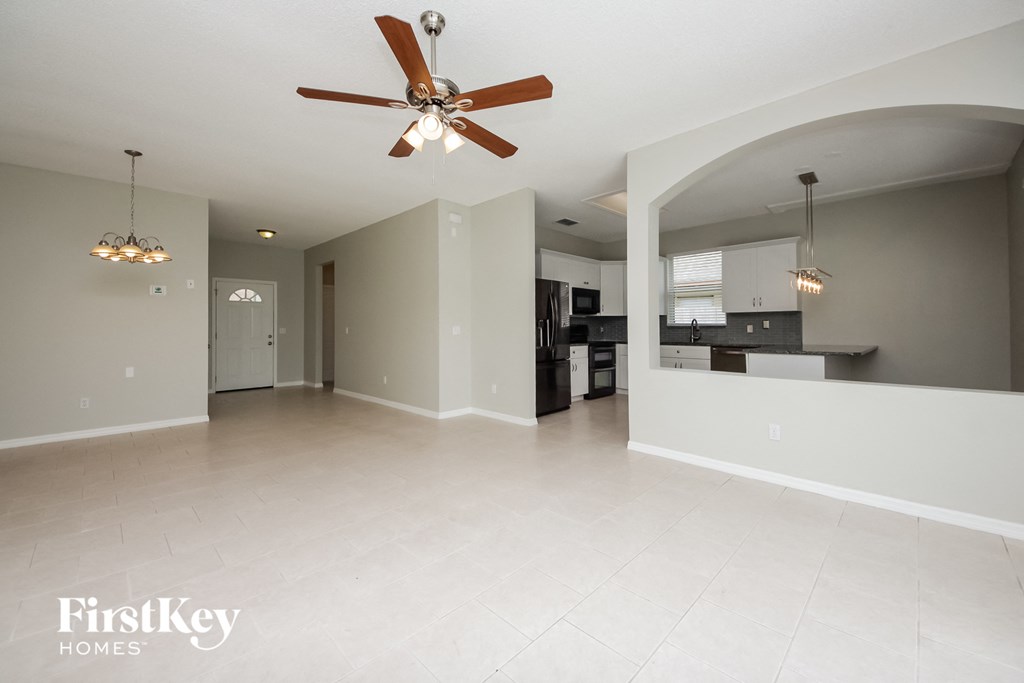an empty living room and kitchen with a ceiling fan
