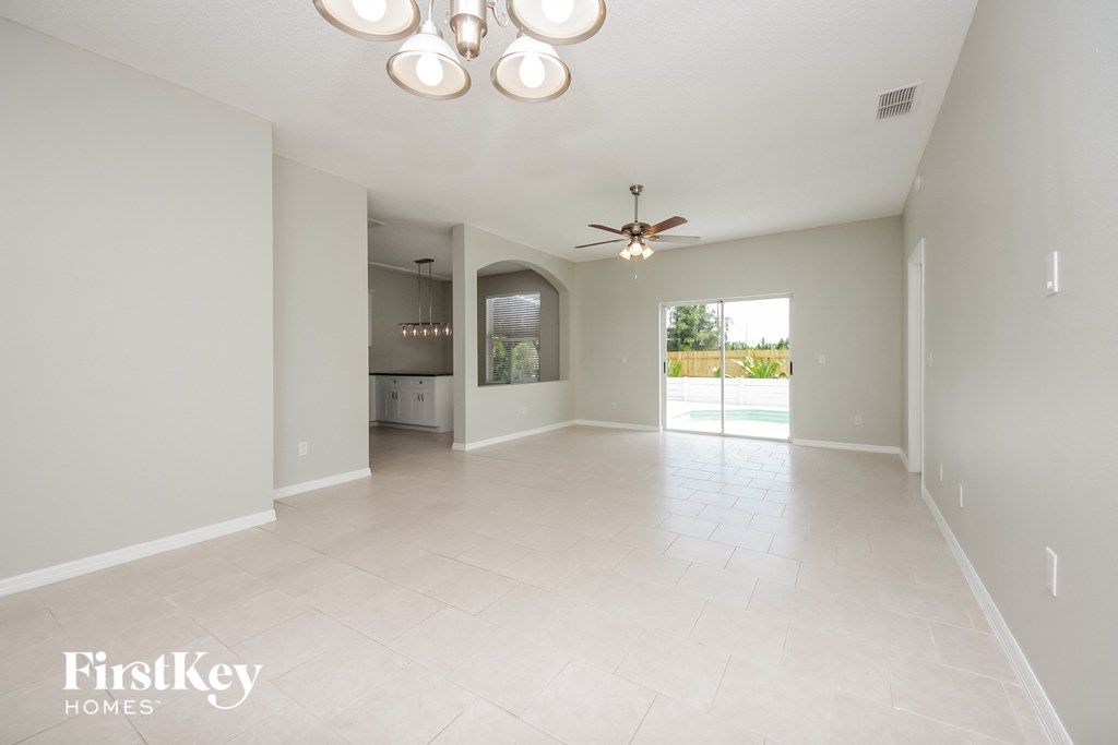 an empty living room and kitchen with a ceiling fan