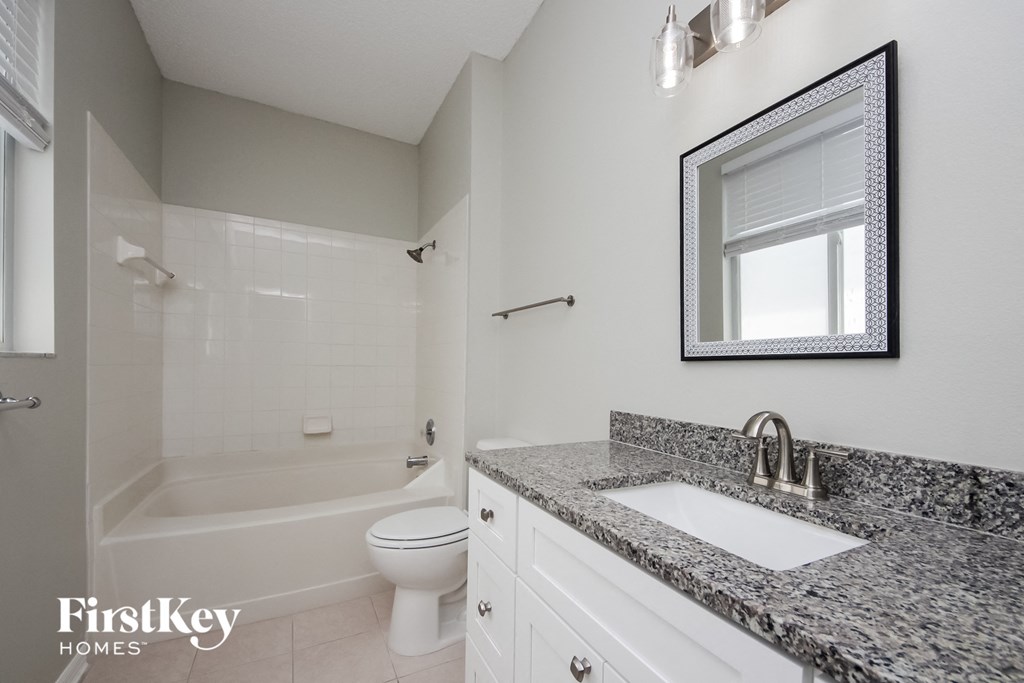a bathroom with granite counter tops and a shower and toilet