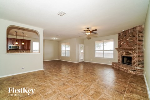 an empty living room with a brick fireplace and tile flooring