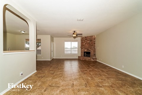 the living room with fireplace and tile flooring and a ceiling fan