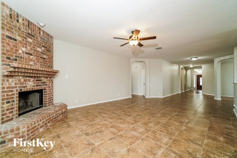 a living room with a brick fireplace and a ceiling fan