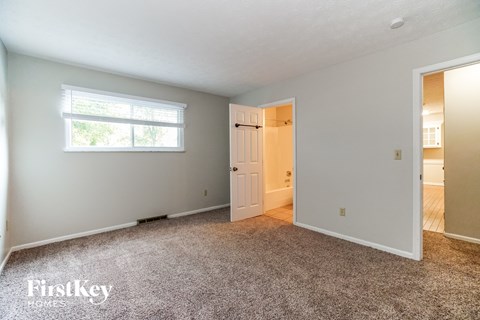 a bedroom with carpet and a door to a closet and a window