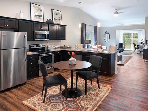 a kitchen with black cabinets and stainless steel appliances and a table