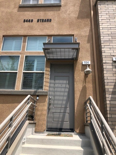 The entrance to a building with a brown door and a sign that reads "6440 Strand".