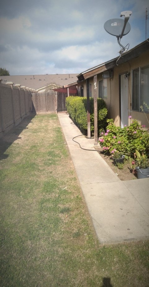 a yard in front of a house with a lawn and a fence