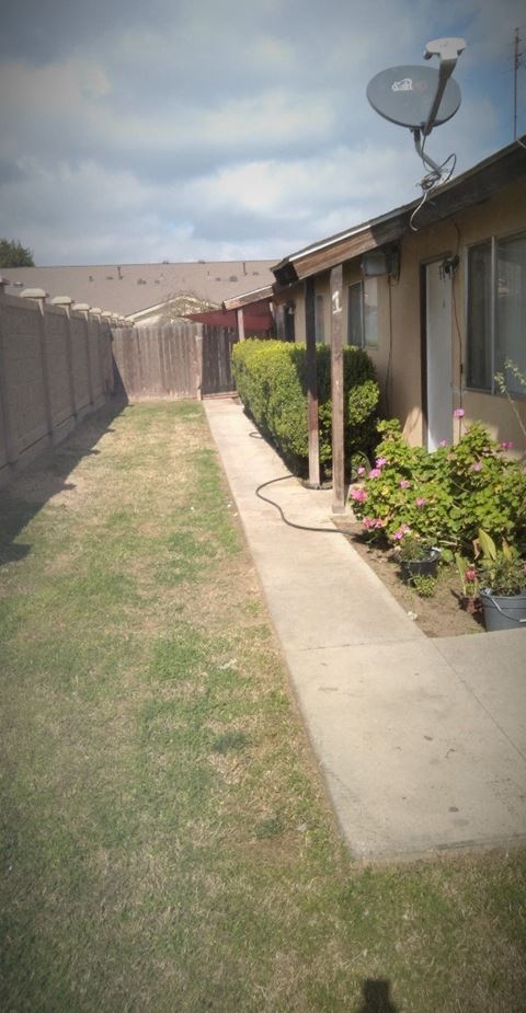 a yard in front of a house with a lawn and a fence