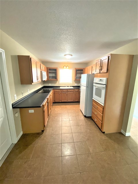 A kitchen with brown cabinets and a black countertop.