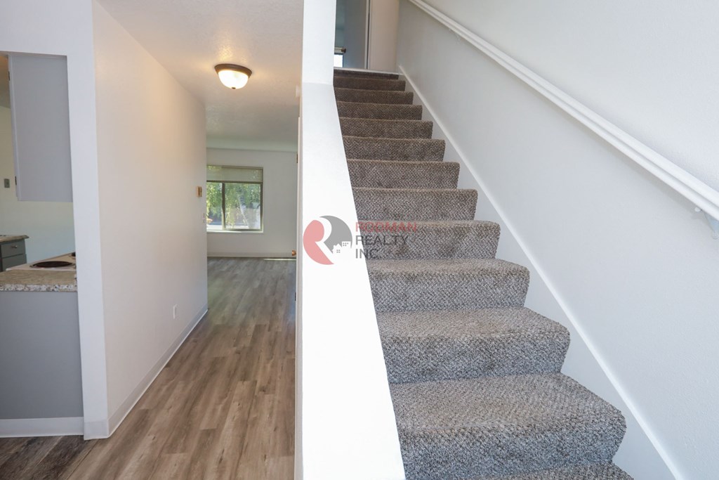 A staircase with a carpeted runner and a white handrail.