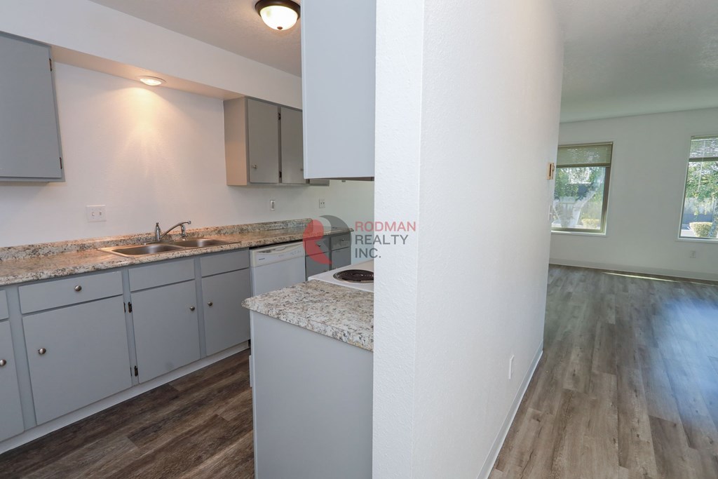 A kitchen with a granite countertop and wooden flooring.